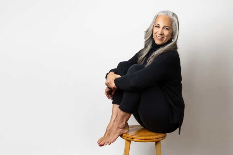 3N5A4511 wide Professional headshot of a mixed race woman wearing all black on a stool